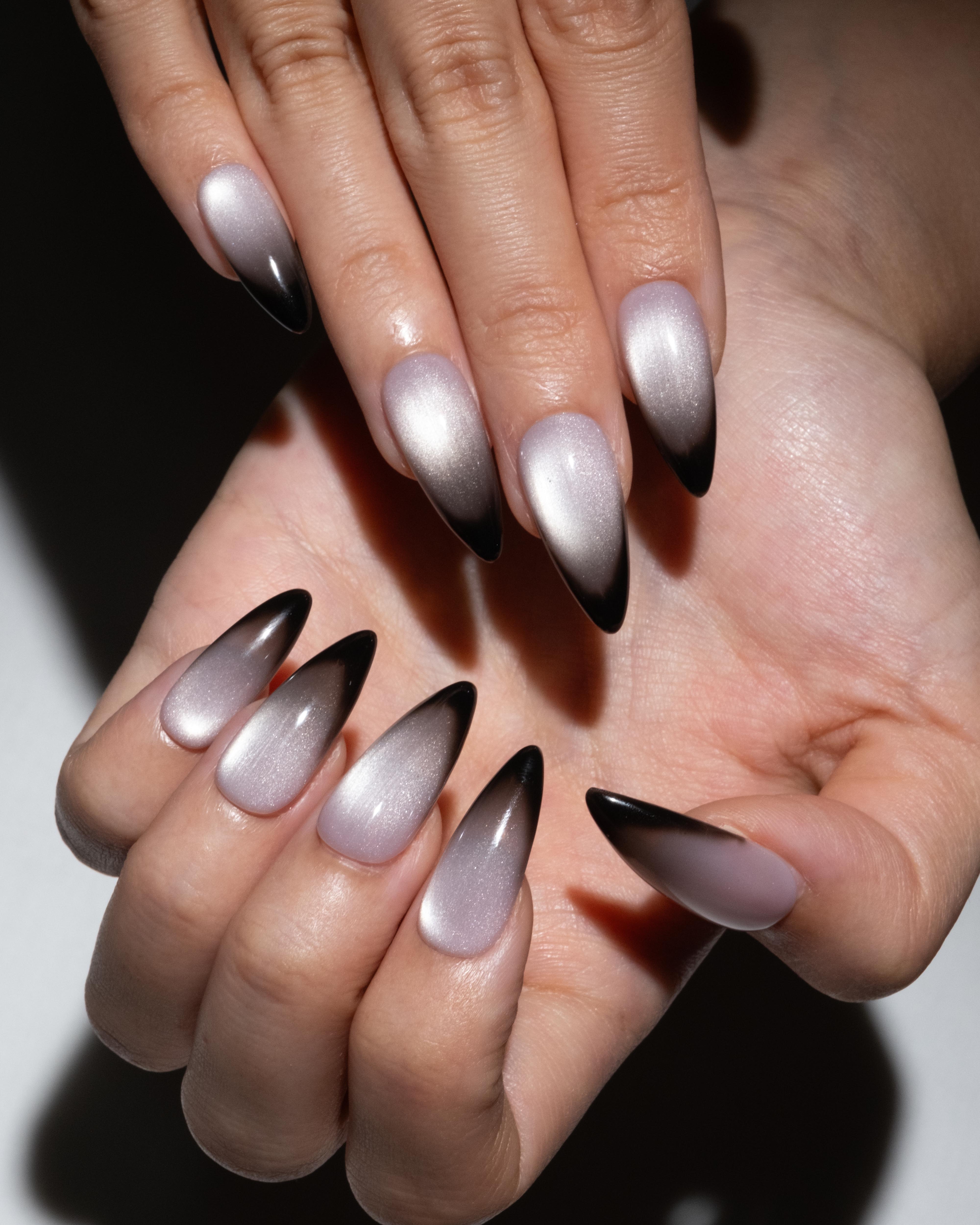 Close-up of hands with gradient nail art on a neutral background